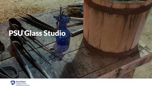Table with glass blowing tools and a wooden bucket. Text says PSU Glass Studio